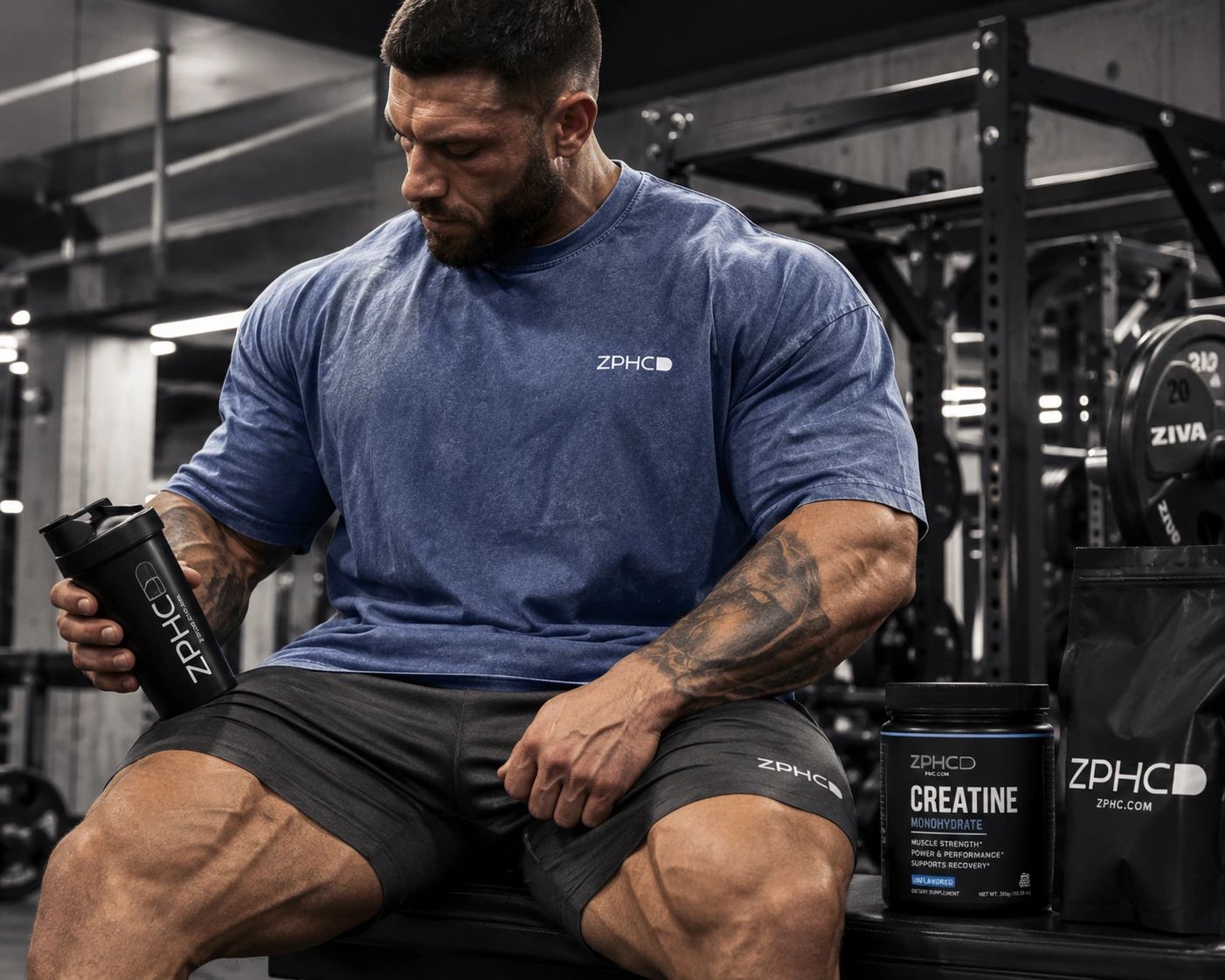 Strength athlete with ZPHC shaker, creatine tub, and supplement bag in a gym.